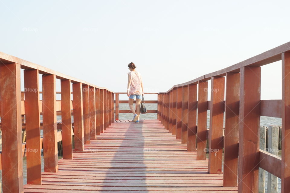 A women waking the bridge path to the sea