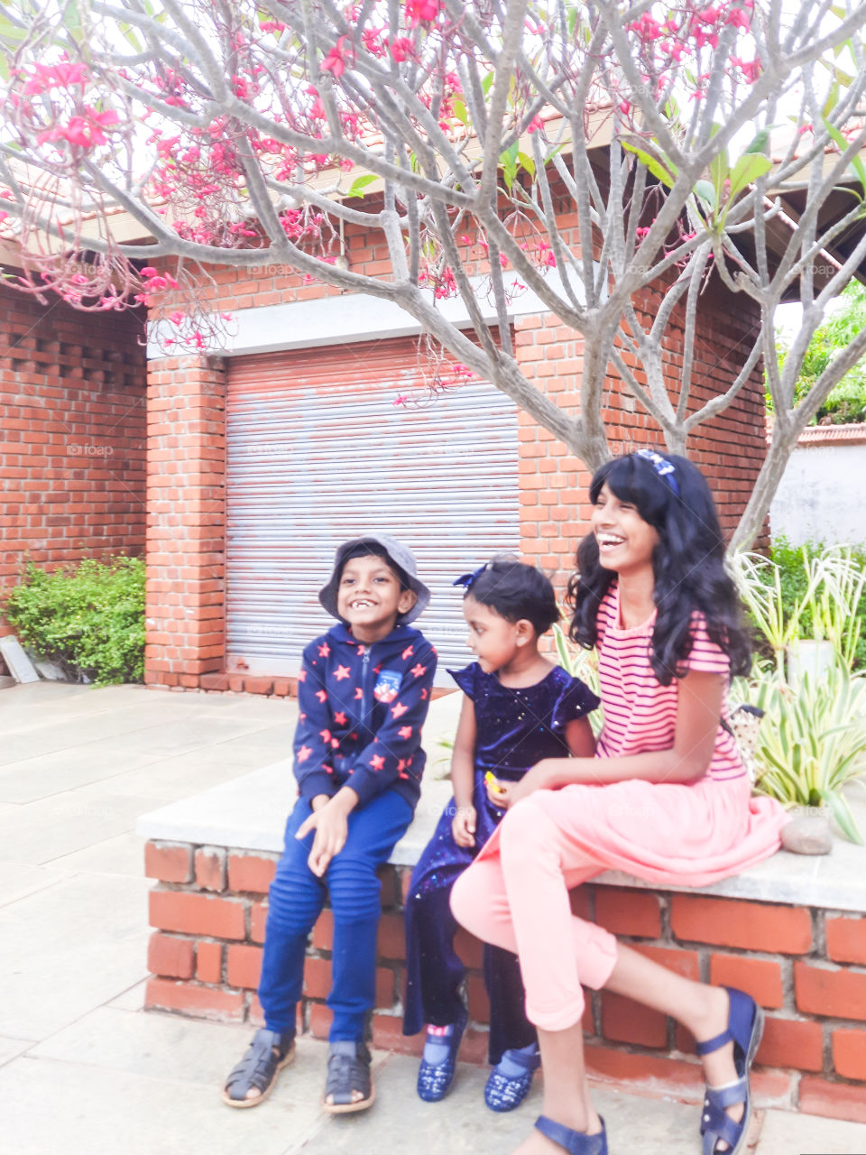 kids posing with a smile under a tree