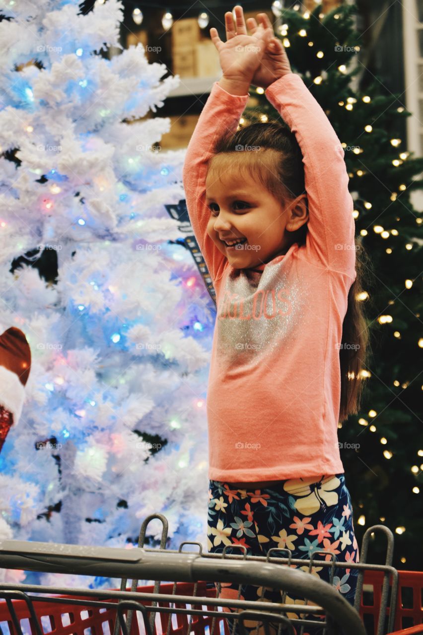 Happy girl standing near christmas tree