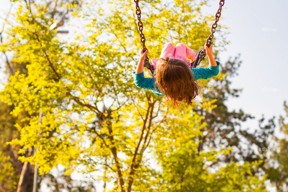 Summer memories of outdoor fun and activities. Image of a girl on a swing having fun at sunset