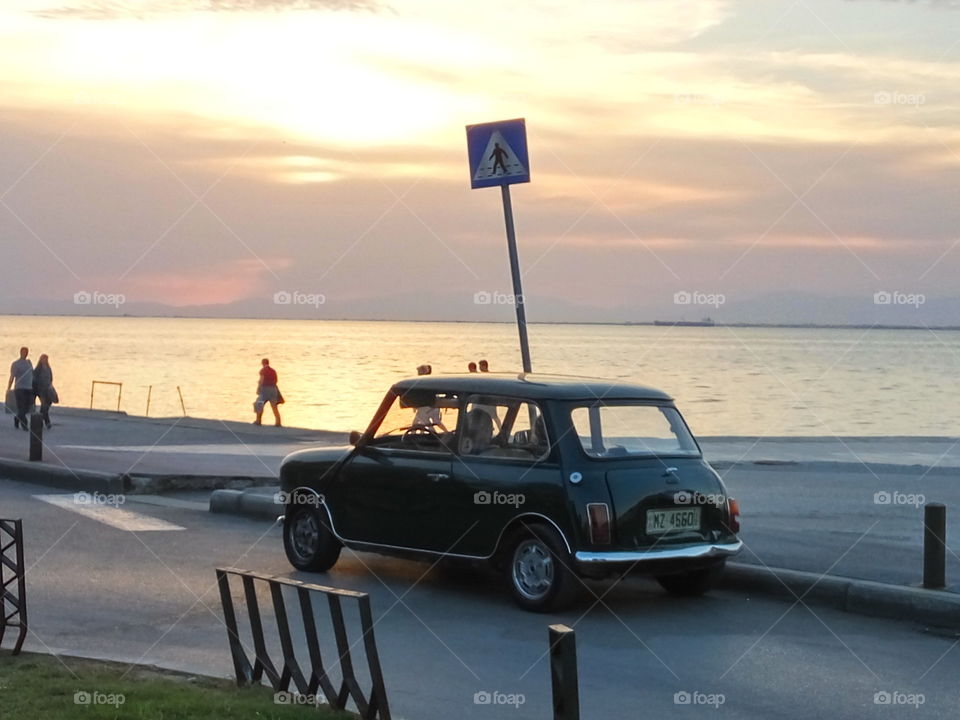 Old couple in their vintage Mini Cooper watching the sunset while relaxing
