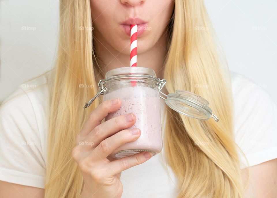 Blonde woman or girl drinking strawberry smoothie
