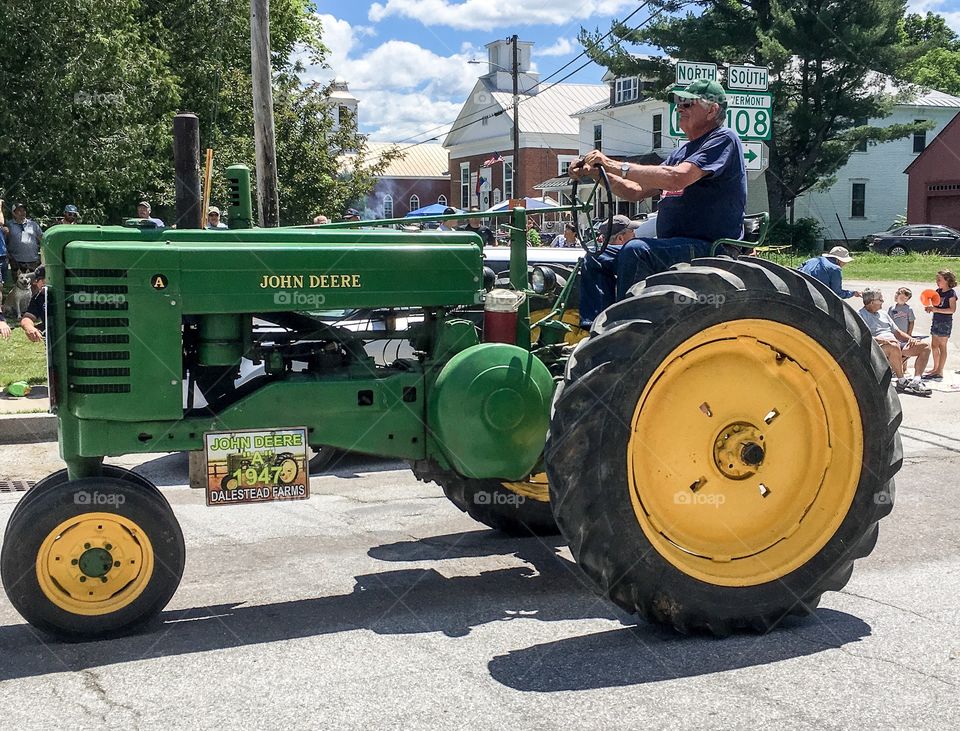 Antique John Deere tractor rolling down the street for a parade in rural Vermont.  