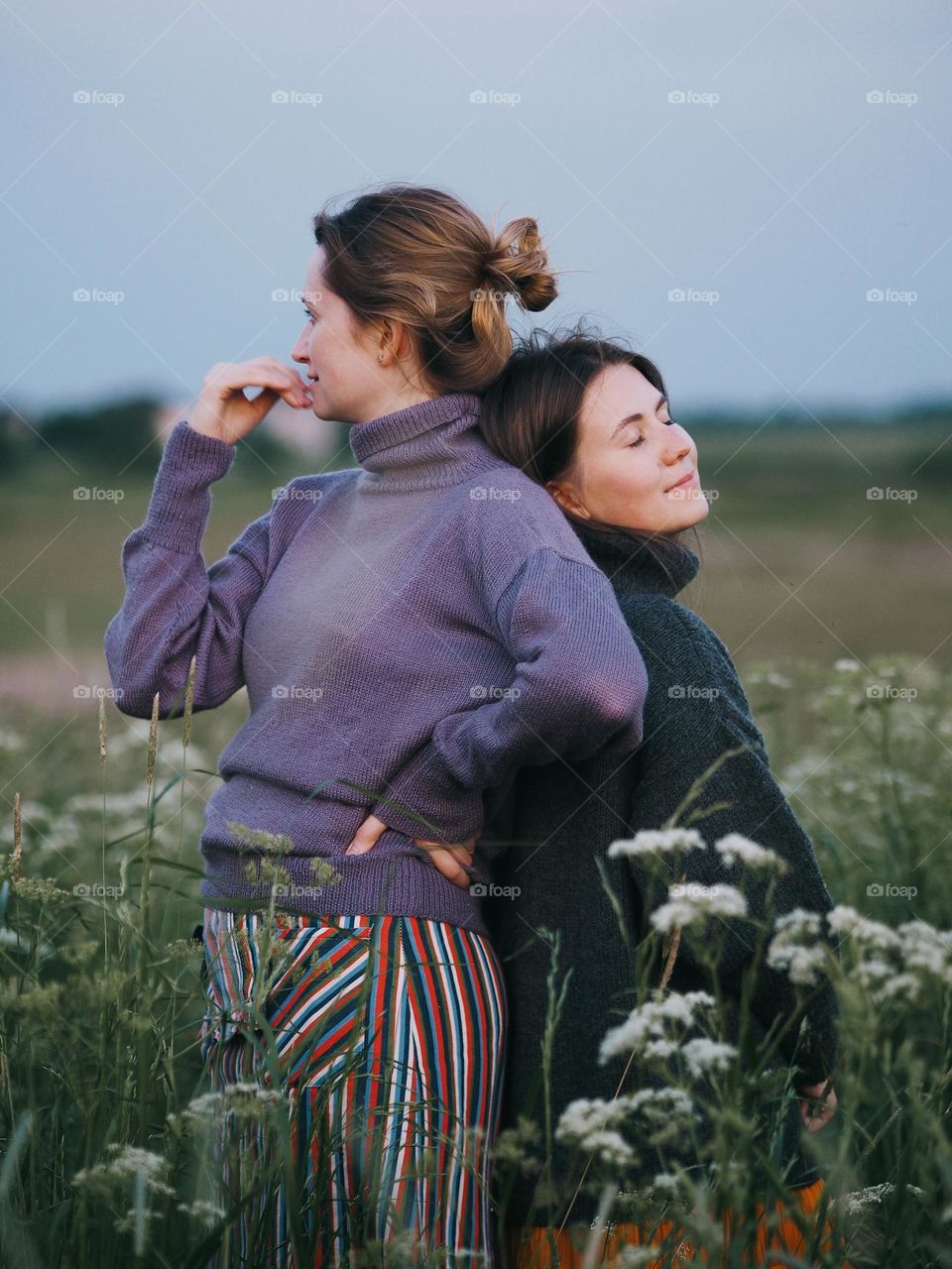 Two young beautiful woman’s standing in field on a summer day, portrait of woman 