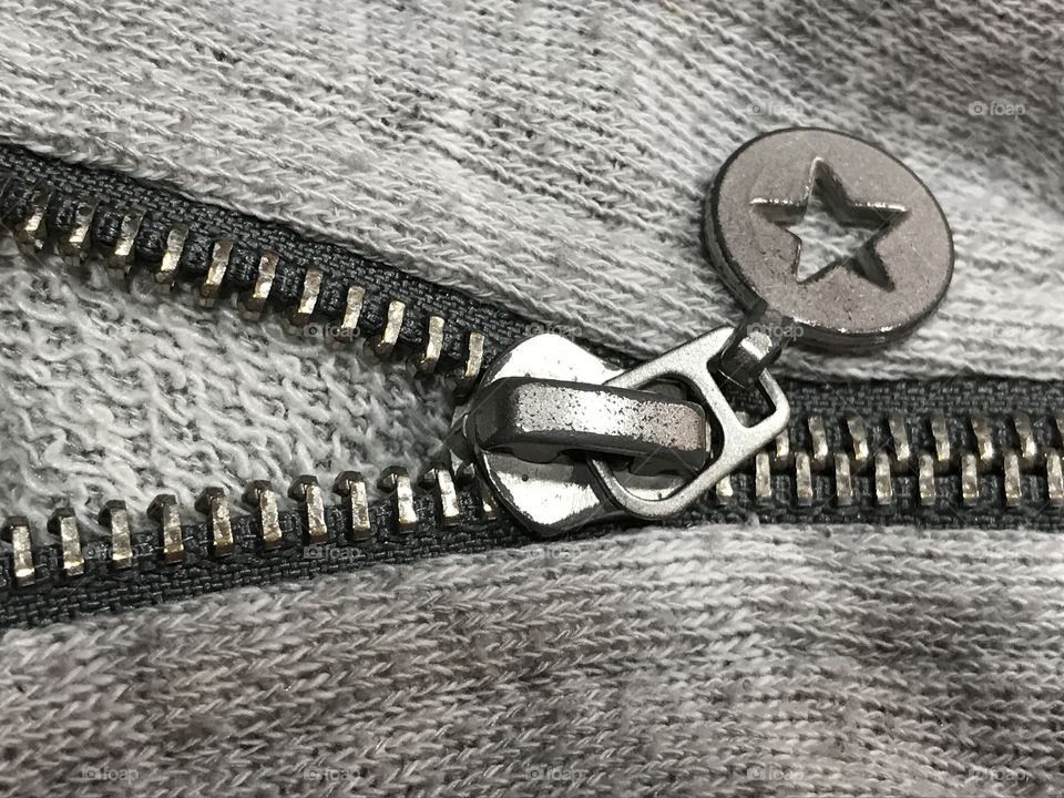 Metal zipper on a gray sweatshirt with a star on it.