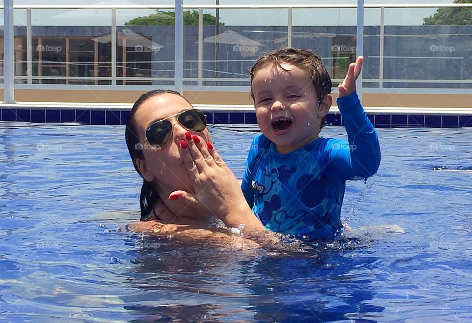 Woman playing with boy inside the pool.