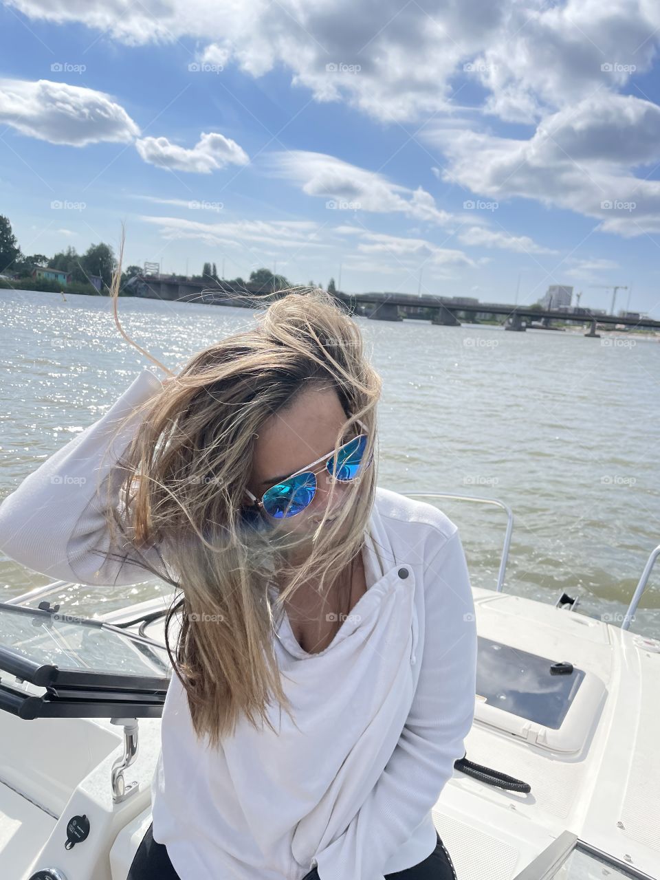 Summertime on a boat. A blond girl with messy hair due to a windy boat ride