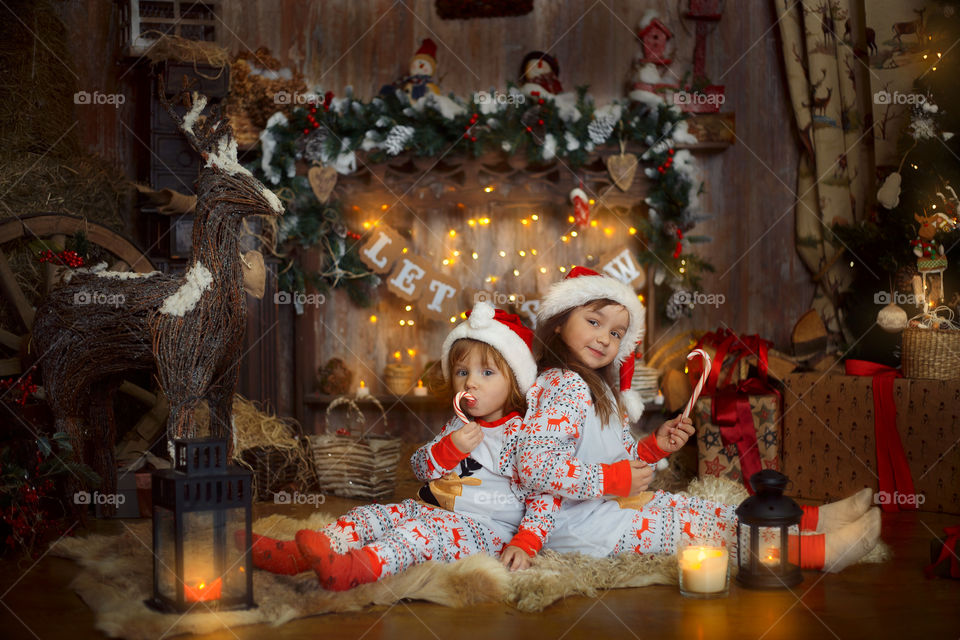 Little sisters near fireplace at Christmas Eve 