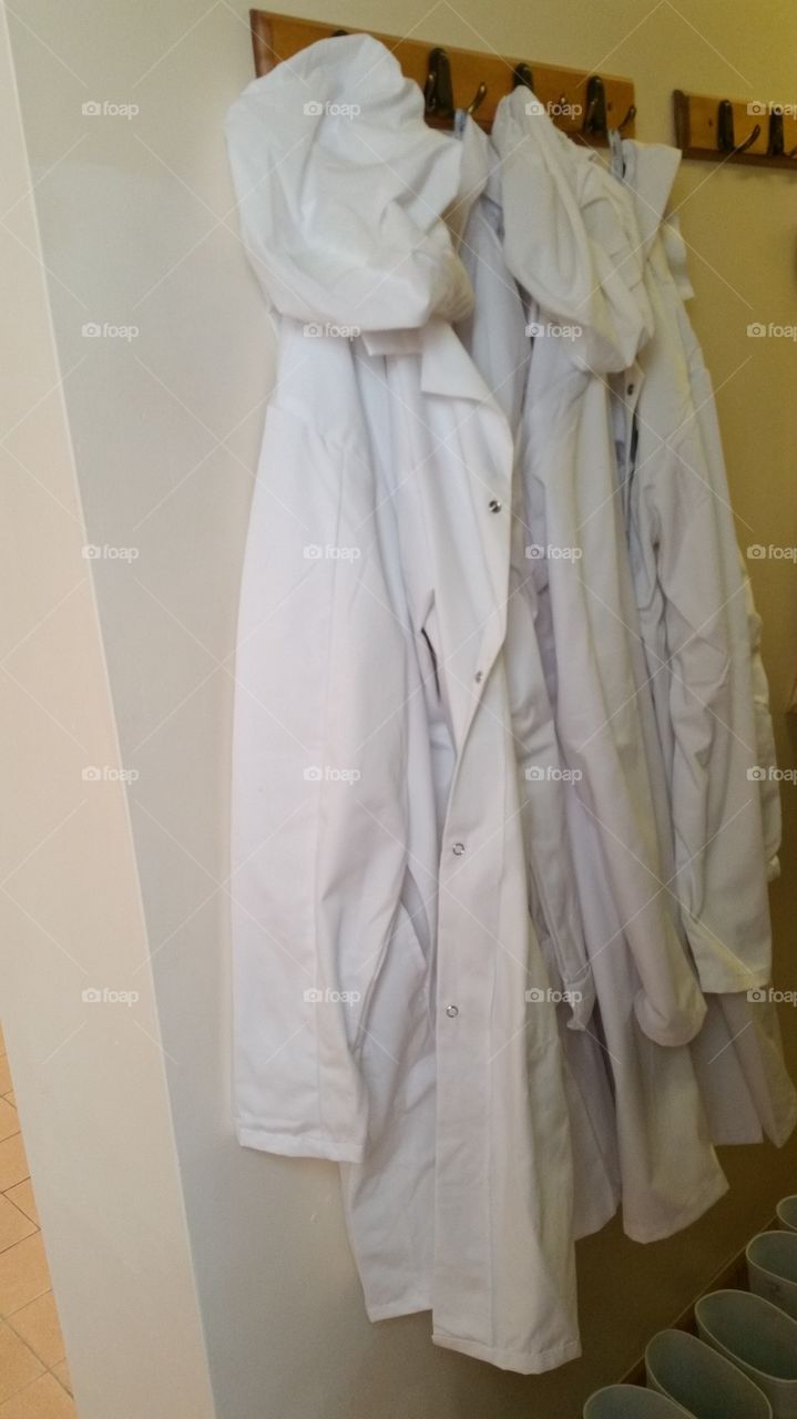 industrial white overalls hanging on pegs inside