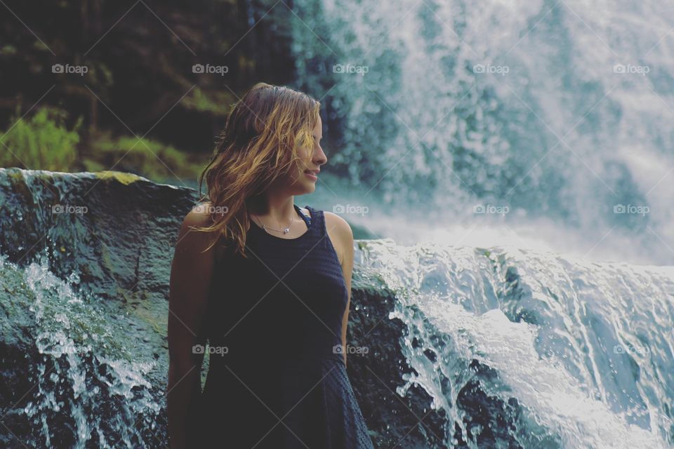 Shot of a girl standing by a waterfall
