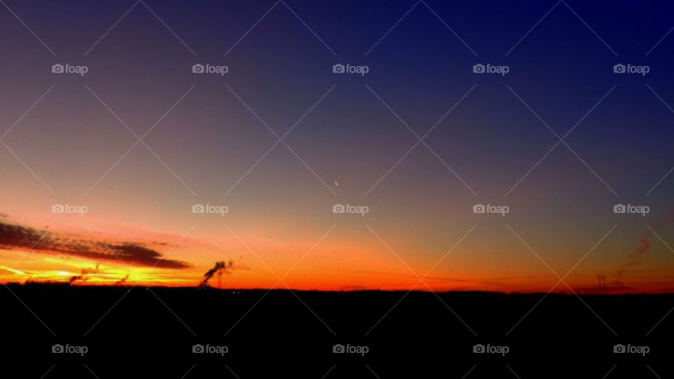 Break of Day. In North Carolina, the first light of dawn cascades high above the sky, dwarfing moon and clouds alike