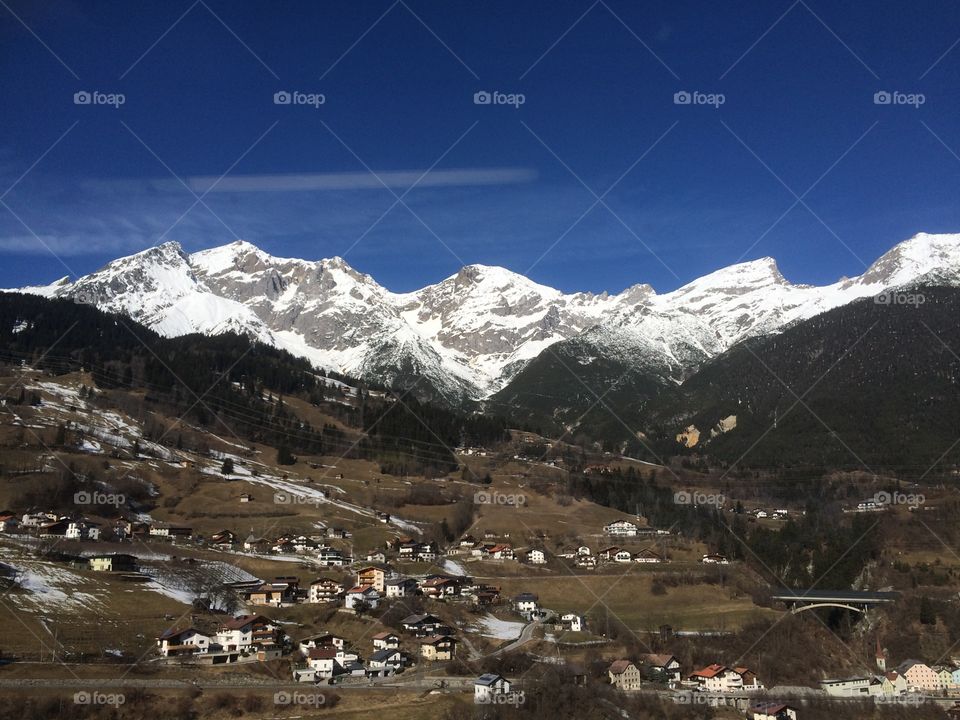 A vie to an alpine village with snowy mountains behind 