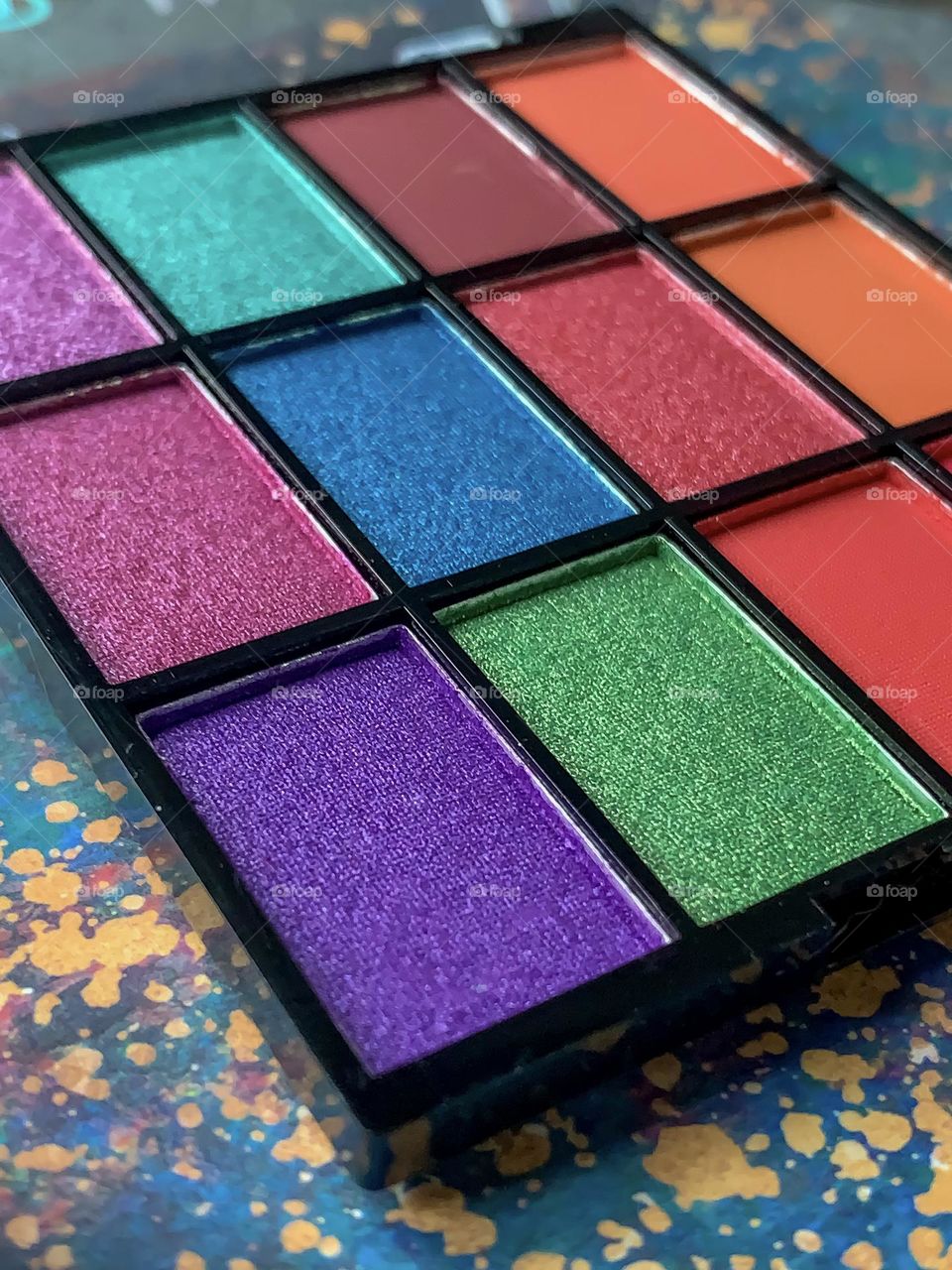 Close up of rectangles of brightly coloured eye shadows and lip gloss