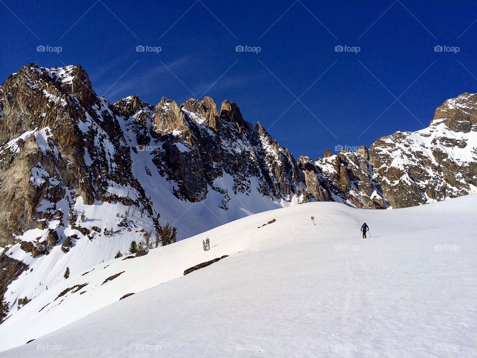 Backcountry skier skinning to a coulior in the majestic Sawtooth Mountains.