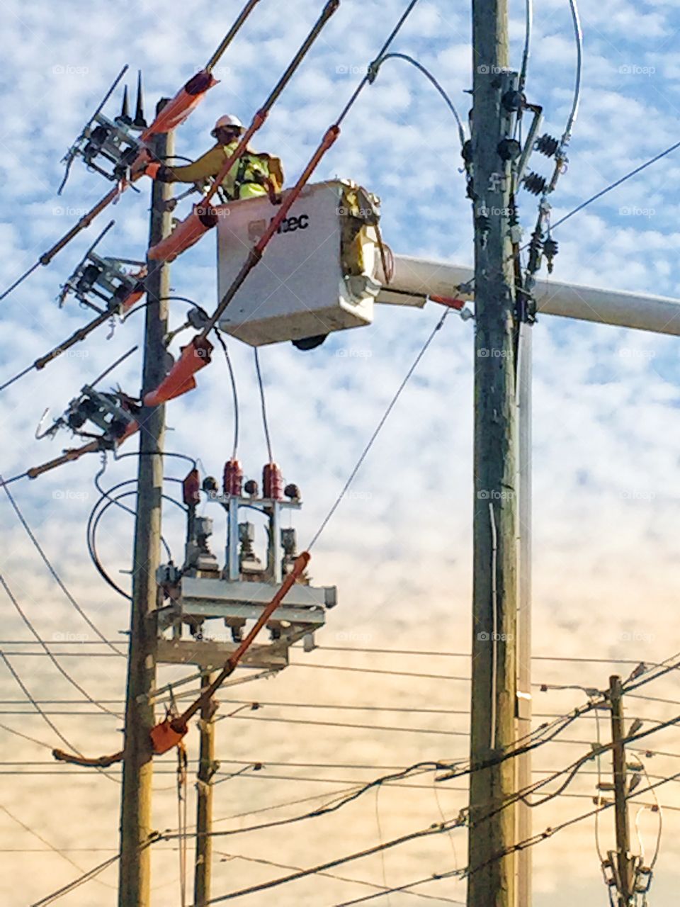 Lineman for an electric company working on power lines from a cherry picker.