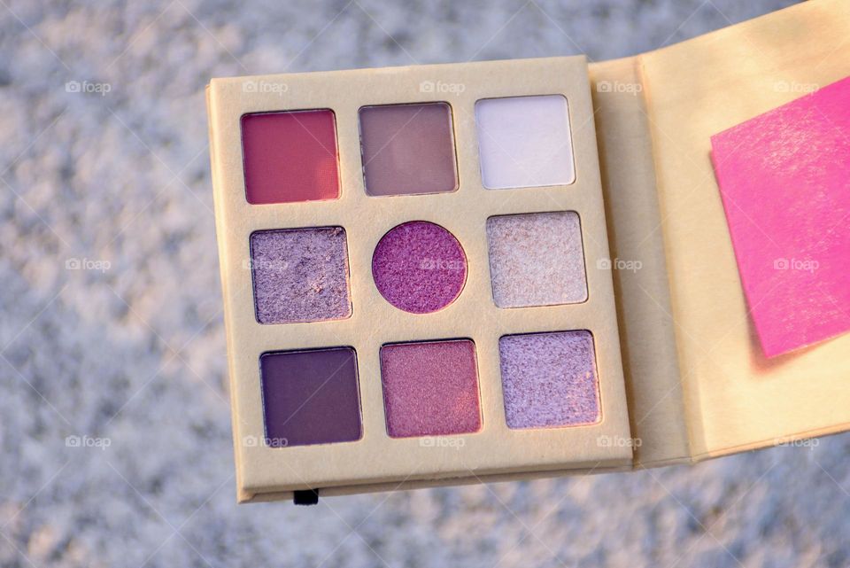 Eye shadow palette on natural stone background.