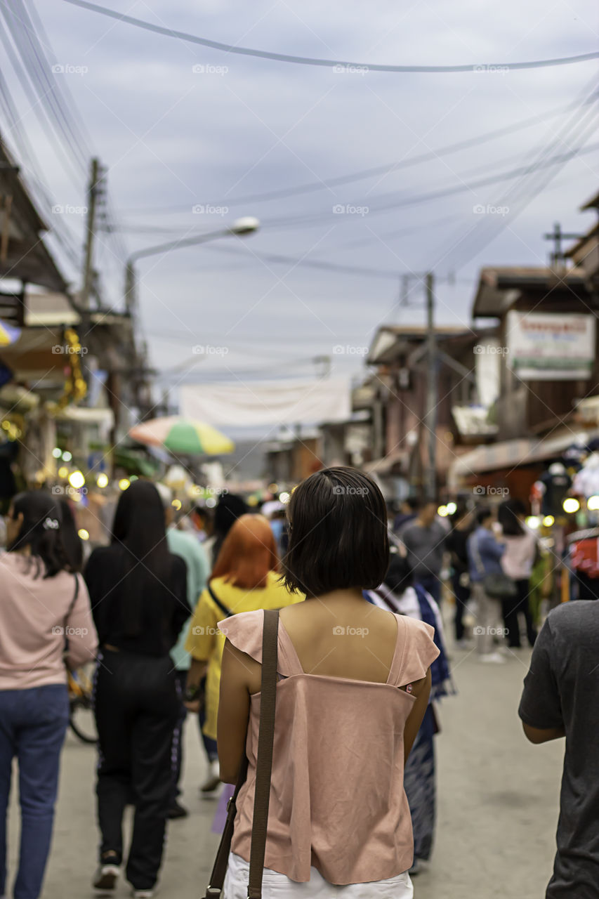 Woman on the street and blurry tourists at Walking Street Chiang Khan, Loei in Thailand.