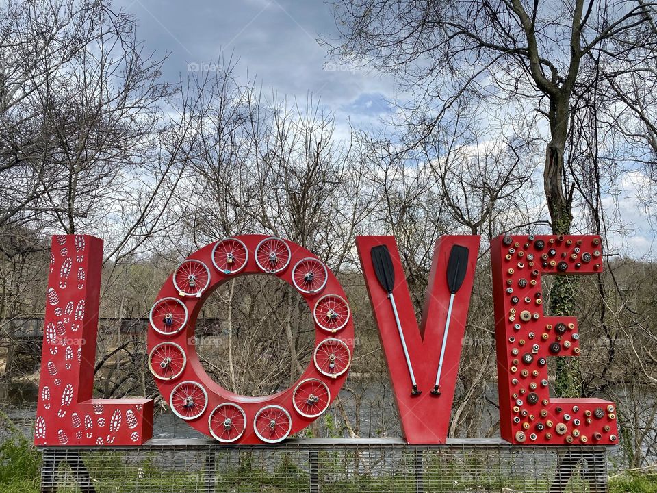 Bright red sculpture of the word love made with athletic equipment 