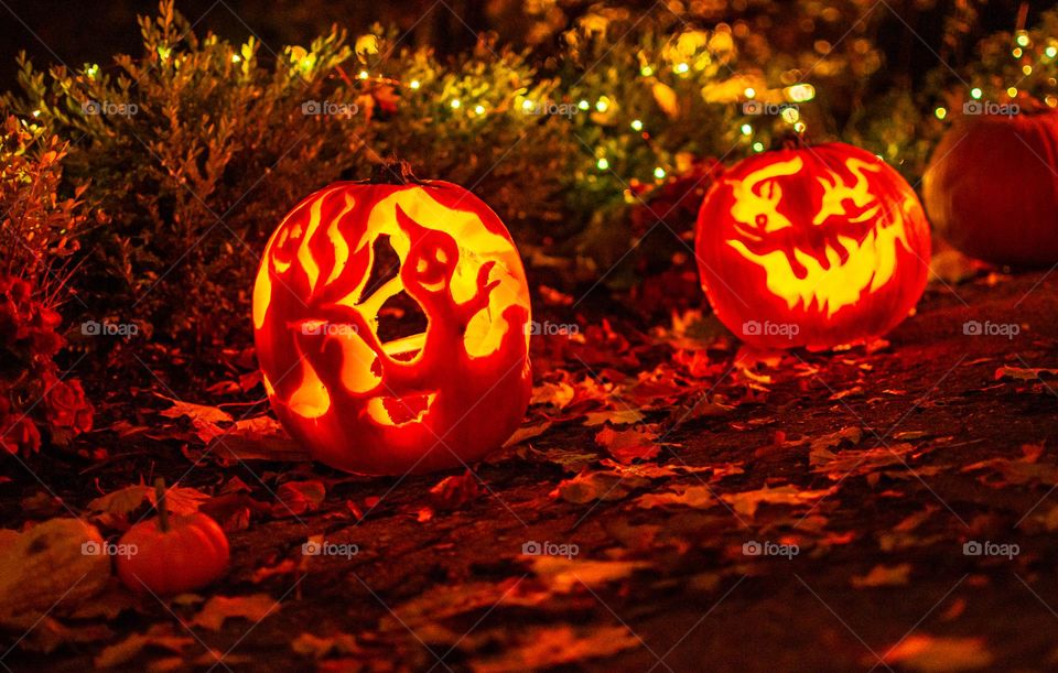 Halloween Jack-o’-lantern illuminated at night holiday decorations and fun Halloween background with autumn leaves on a pathway for trick-or-treat 