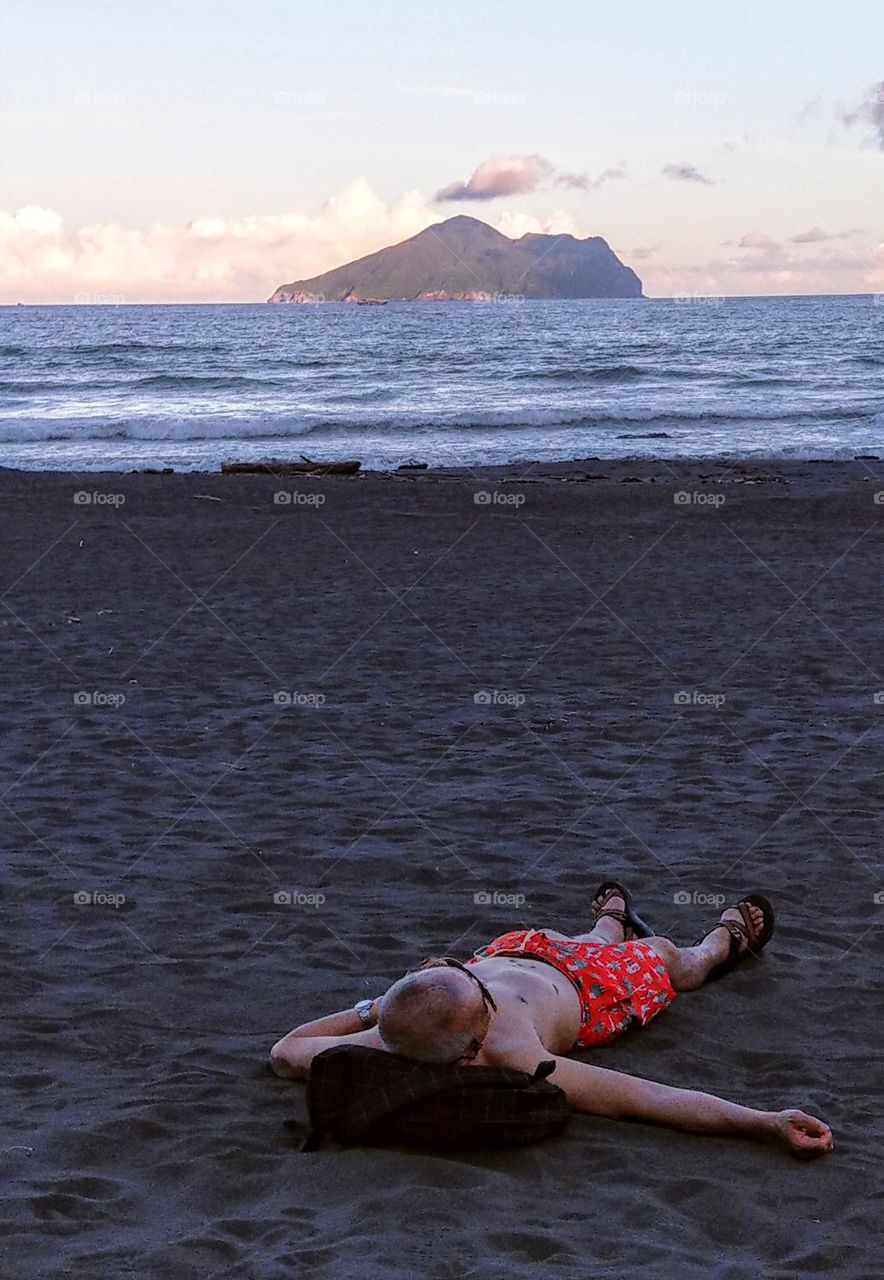 The memories of summer: after people went home, summer's beach had already calmed at dusk. I found a man was lying on the beach. the sea breeze was blowing, he enjoyed this cool wind, relaxed himself, his body and mind should be very comfortable.