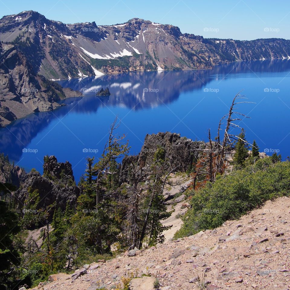 The rugged rim reflecting in the stunning Crater Lake on a beautiful summer morning in Southern Oregon. 