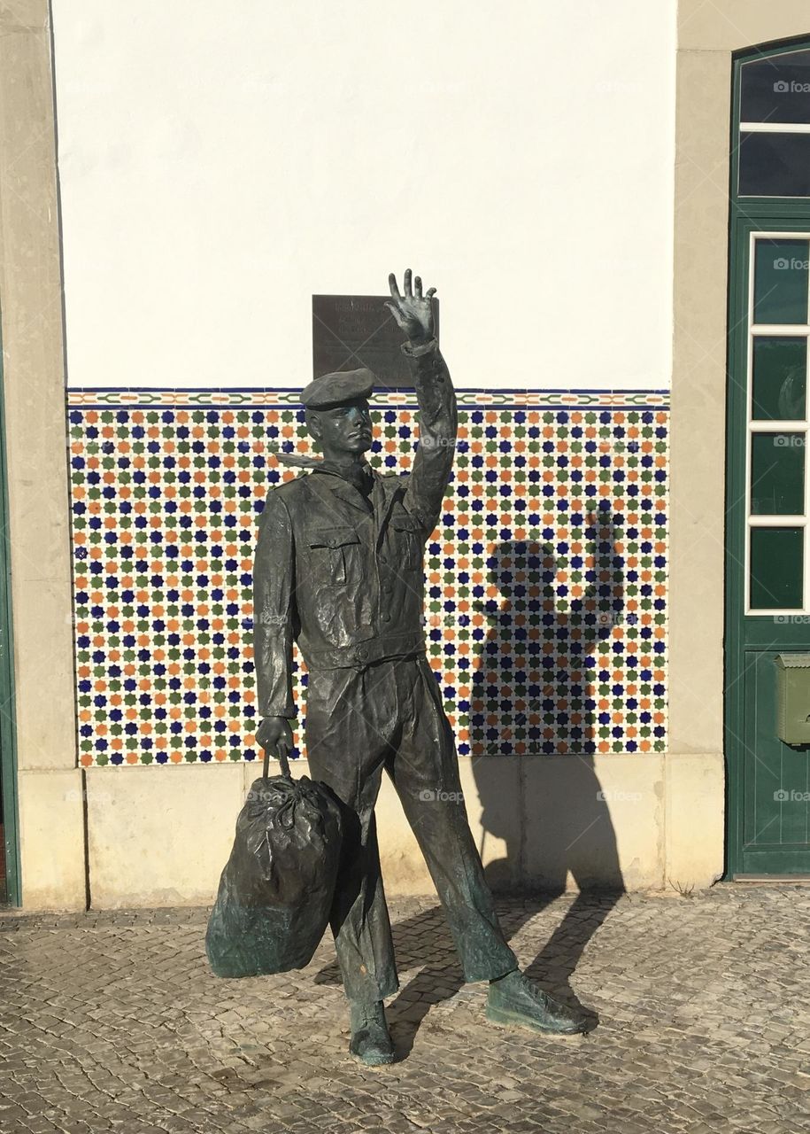 Traveler statue in city with its shadow 