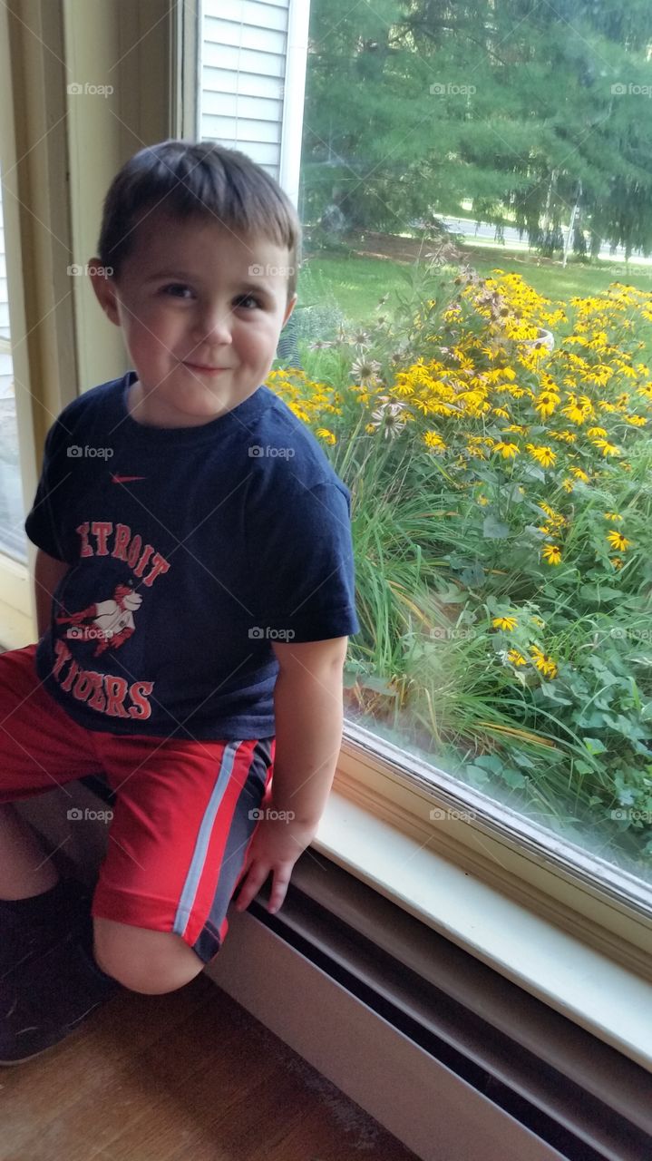 Close-up of a boy sitting on window sill