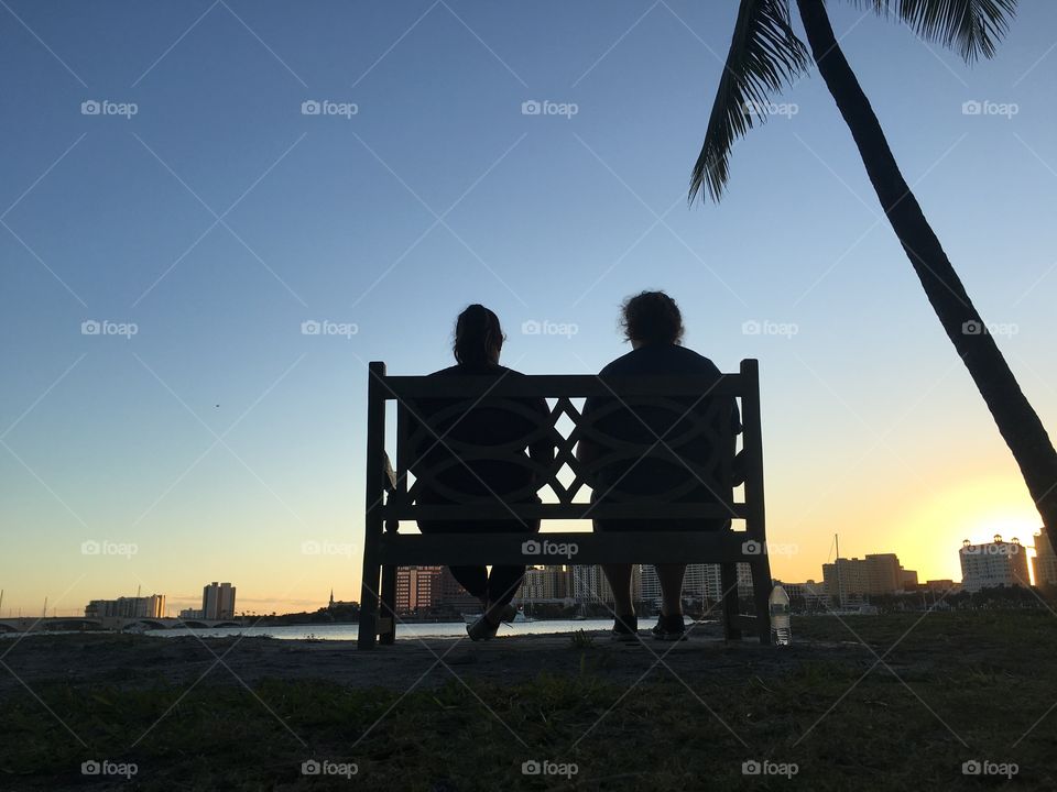 Silhouette of two woman sitting on bench