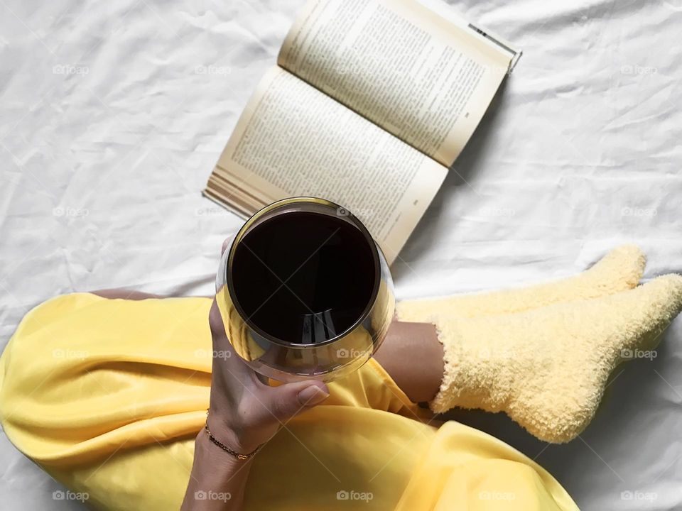 Red wine and book in cozy bed 