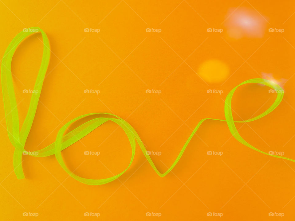 A very important four letter word in yellow ribbon on yellow orange background. Yellow is also the color of friendship.