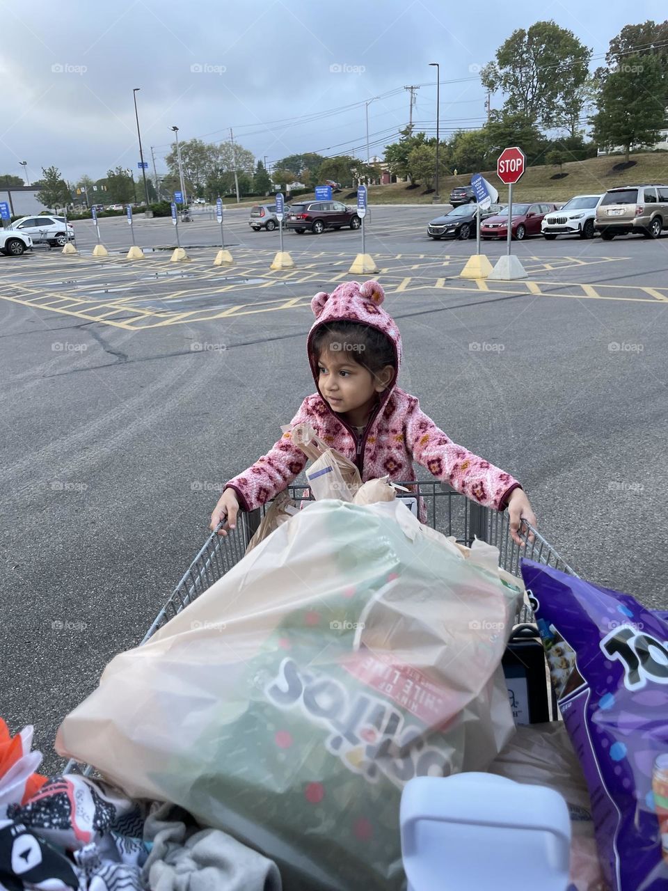 Toddler hangs on to outside of a shopping cart, the keeper of the groceries, riding on the cart, fun with shopping 