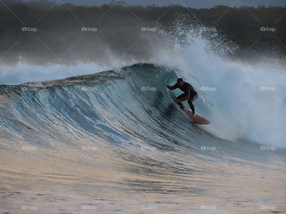 Moods of summer - surfer surfing inside a barrel wave at sunset on the Australian coast.