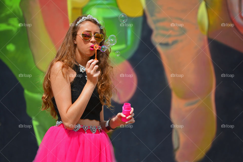 Woman wearing heart shape sunglasses blowing soap bubble