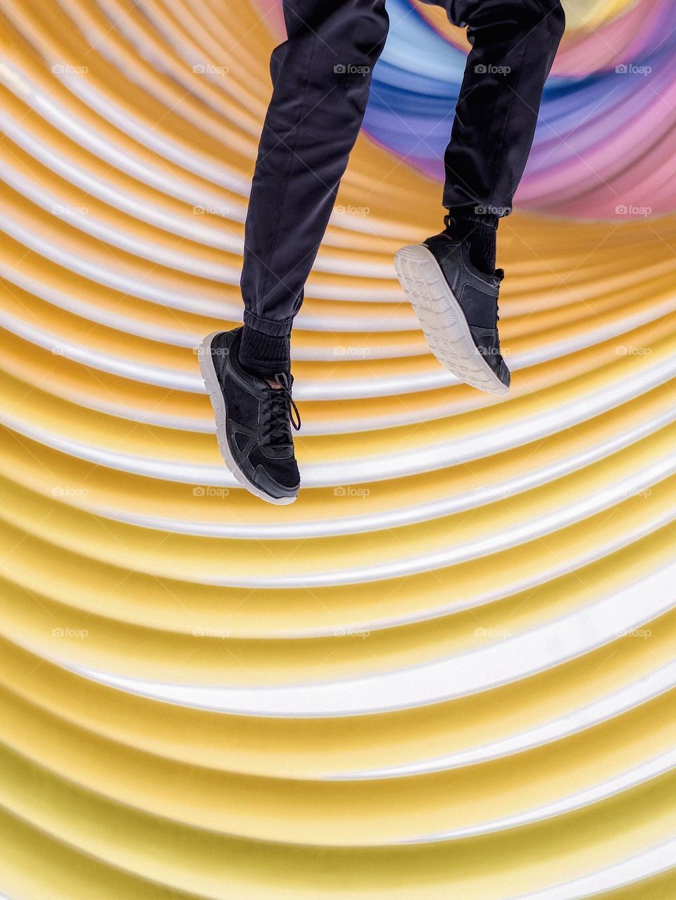 An upside down photo of a boy with legs up in the air against colorful curves structure