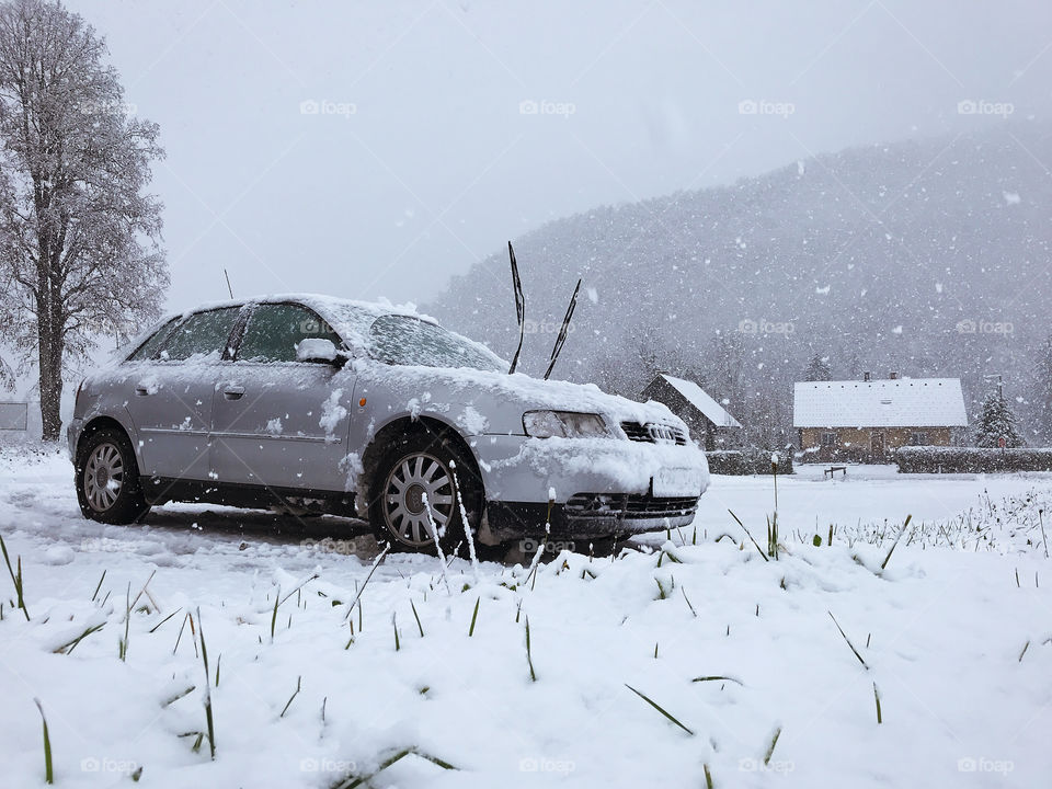Scenic view of the winter landscape. And snow covered car in snowfall in winter in Slovenian village. My road trip.
