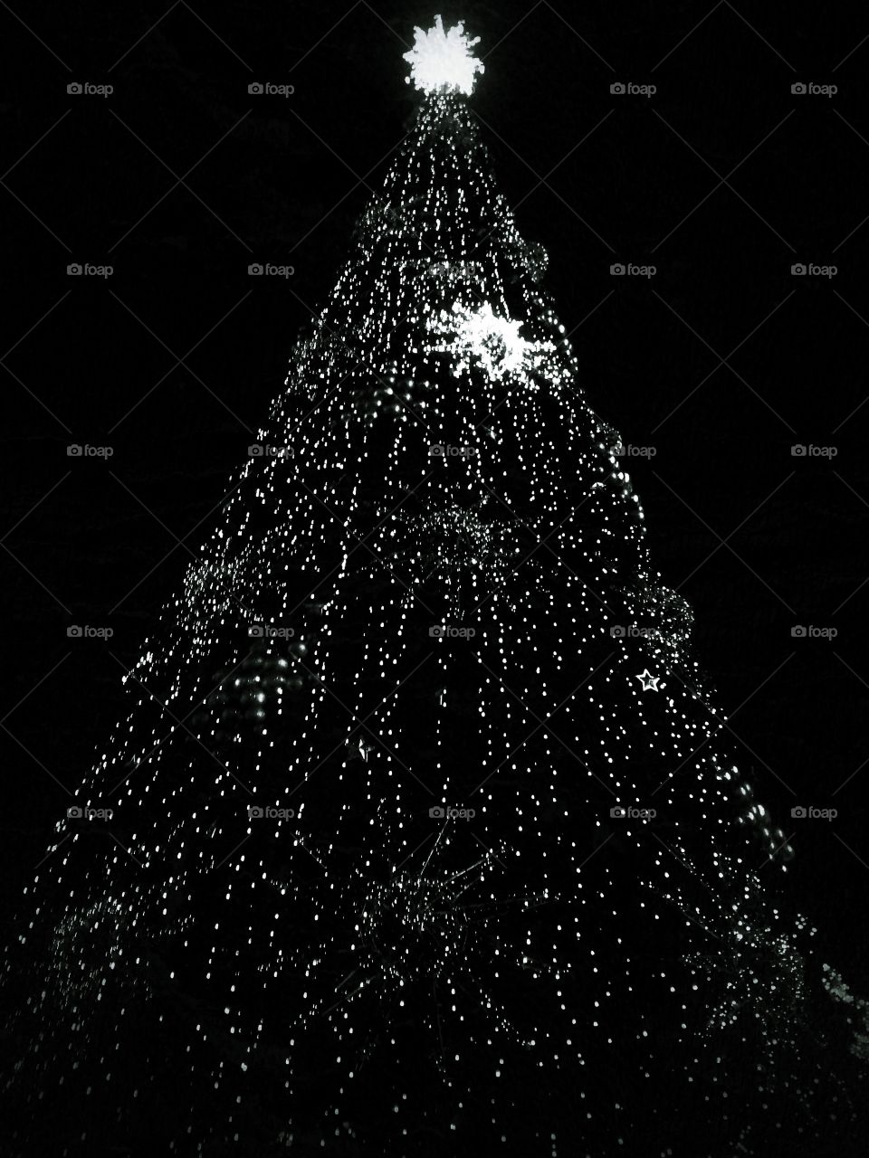 Bright colored illumination on artificial Christmas fir tree in the evening on black sky background in Moscow, Russia