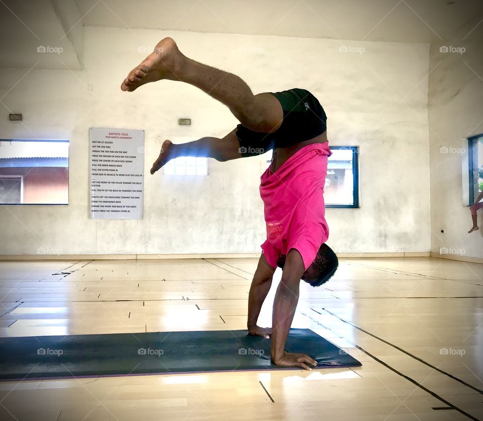 A male yogi gets into a hand stand in a yoga studio 