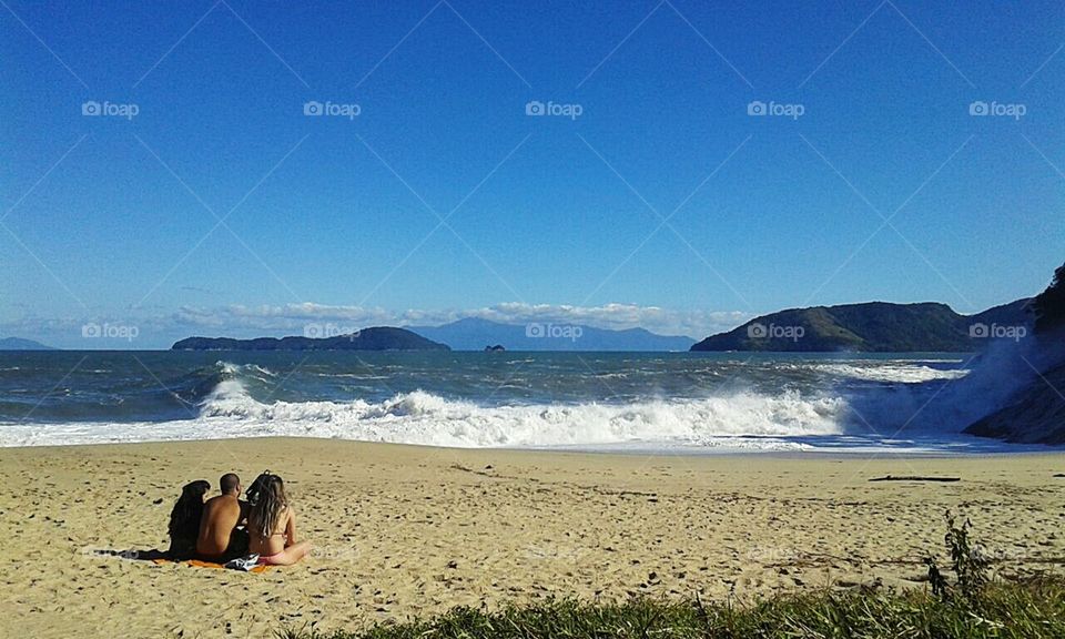 Pessoas contemplam as ondas, as marés na praia, ressaca.