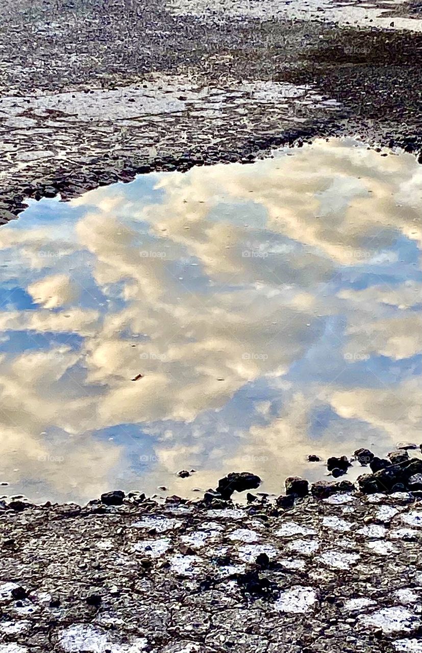 Puddle with reflection of clouds and sky