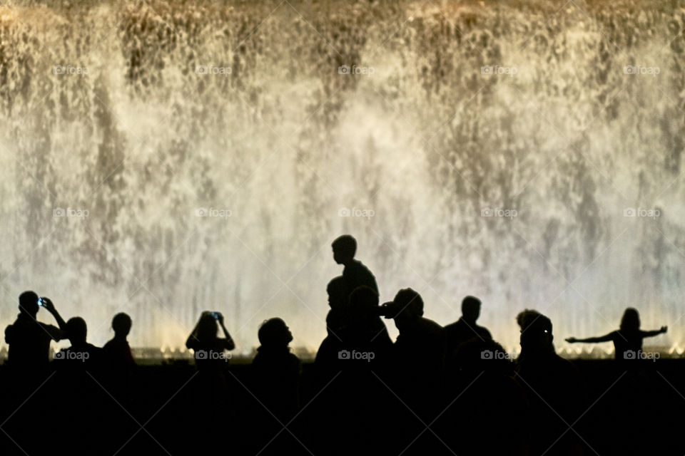Silhouette of people in front of fountain
