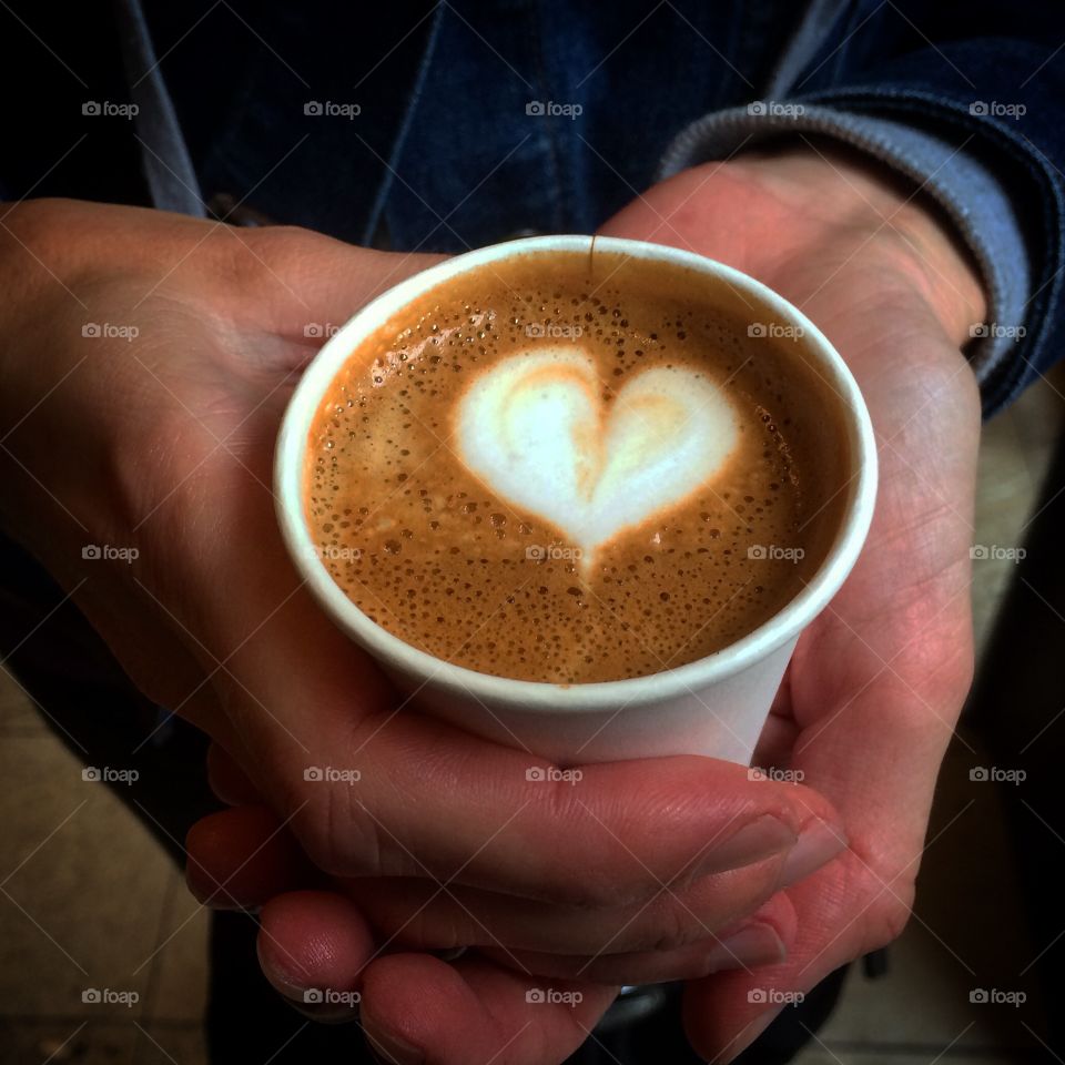 Coffee with a heart with  hands around cup 

