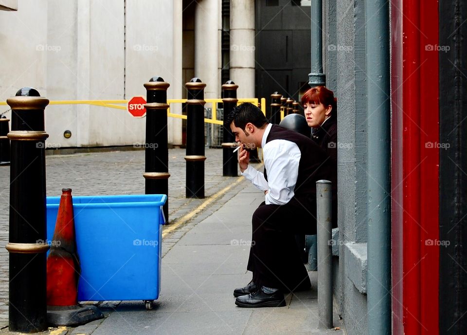 Candid shot of hotel workers taking a quick cigarette break outside the back entrance. 