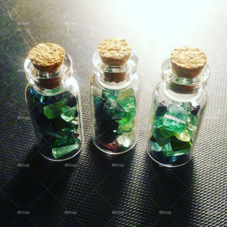 rough tourmaline in three mini glass bottles