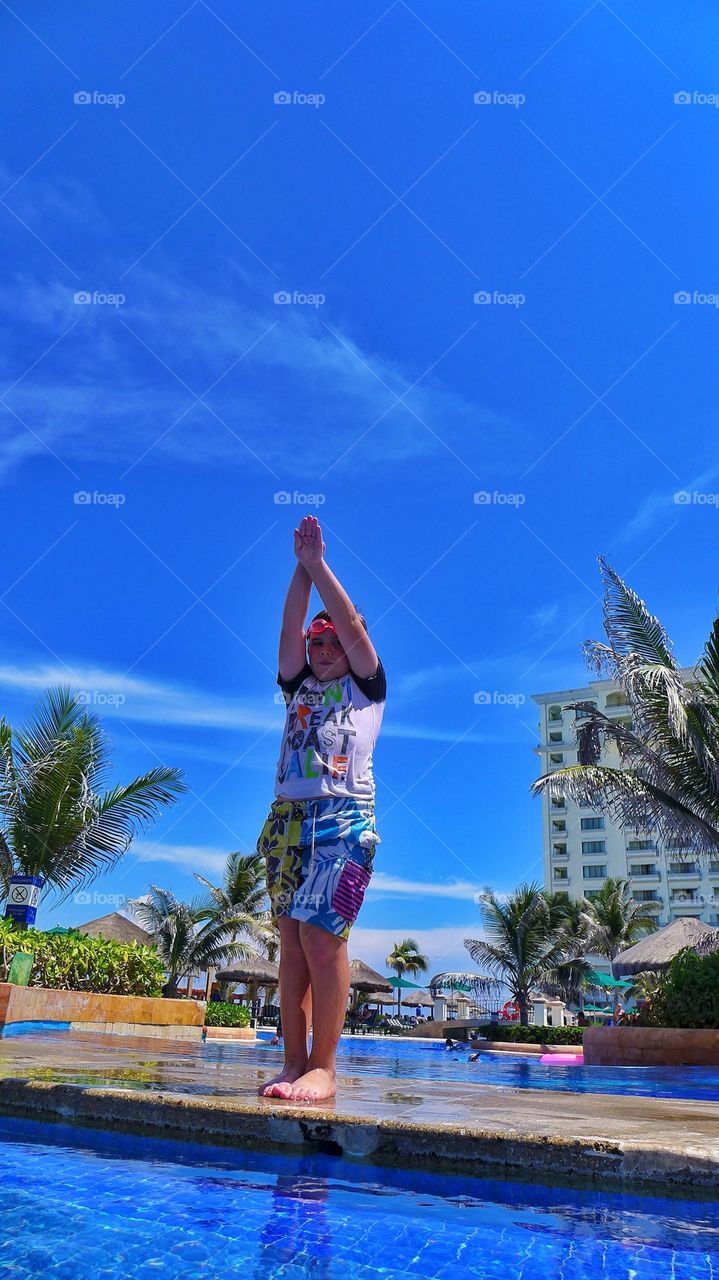 Young kid about to take a deep dive into beach pool in luxury resort