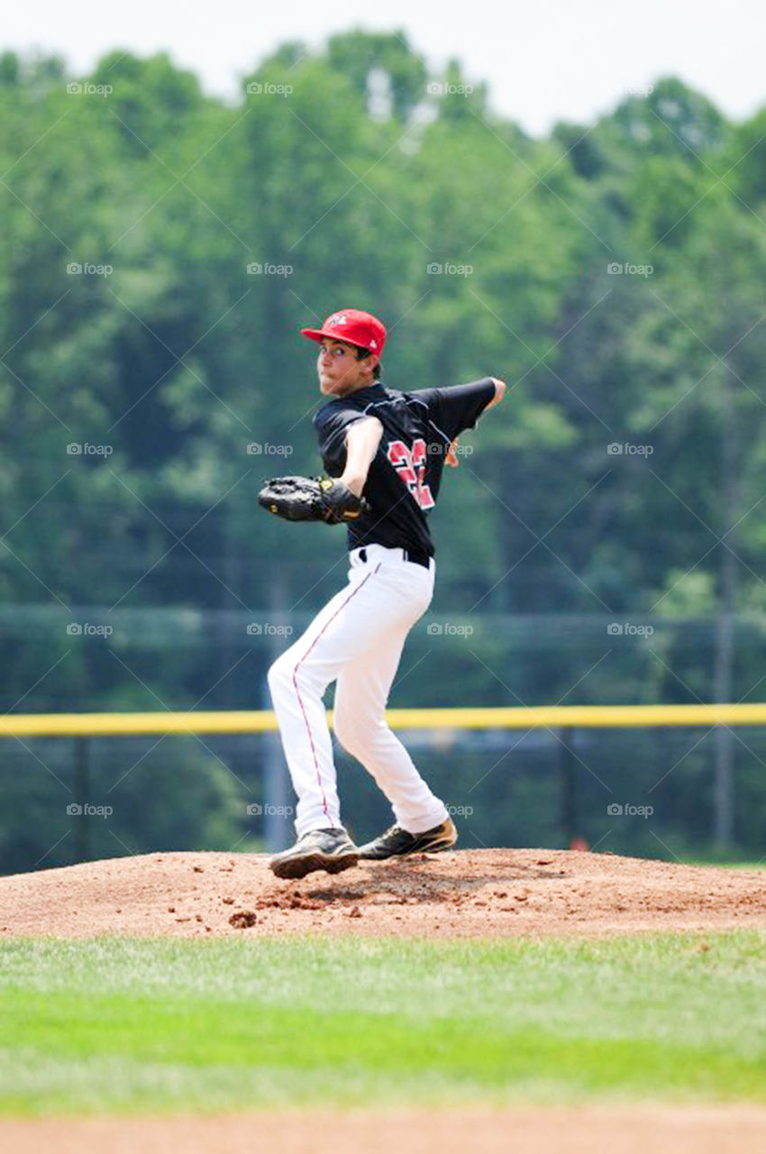 In the stretch. young pitcher stretches to throw ball