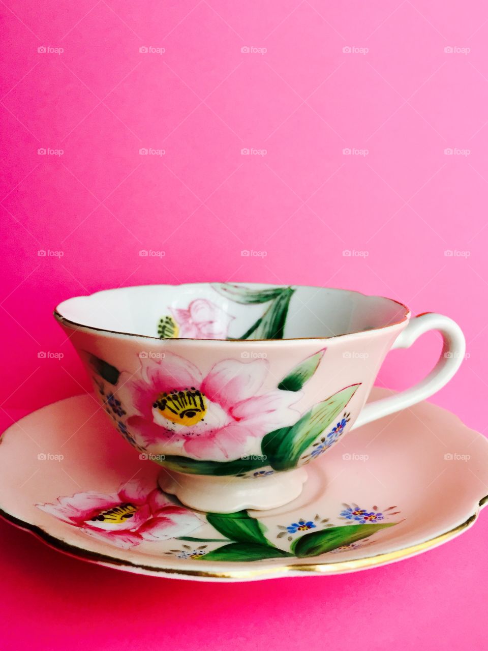 Antique, hand-painted, floral, fine china teacup on a pink background 