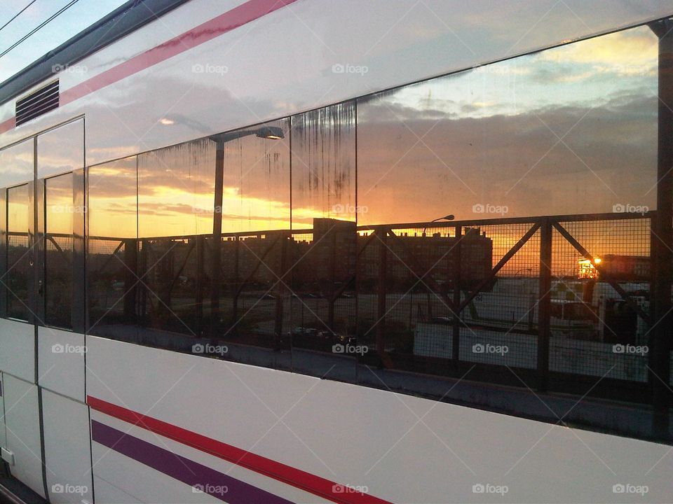Urban sunset reflected in the windows of a Spanish commuter train