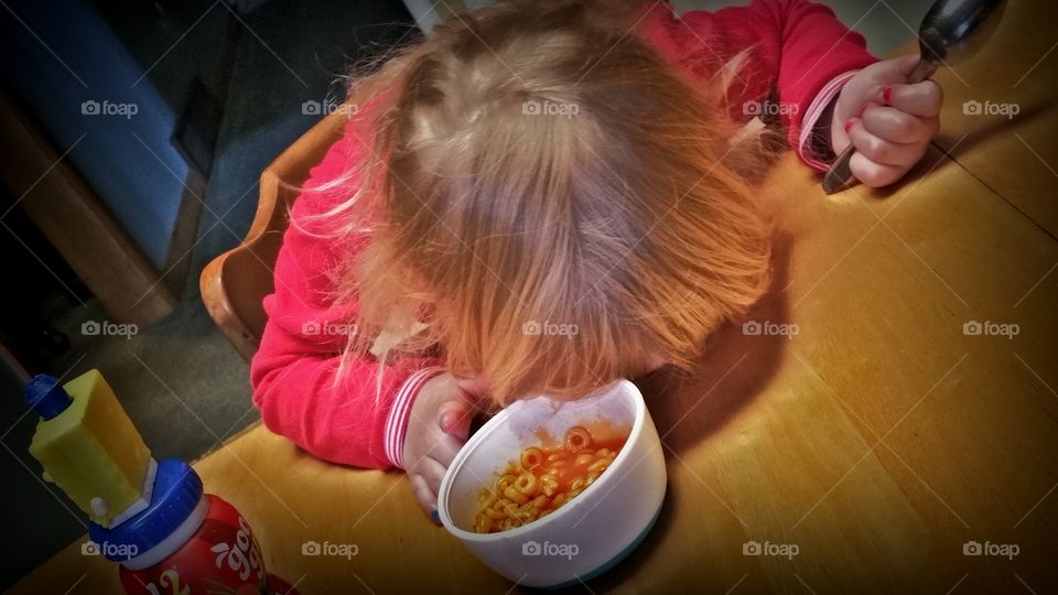 Child resting his head on table near bowl of food