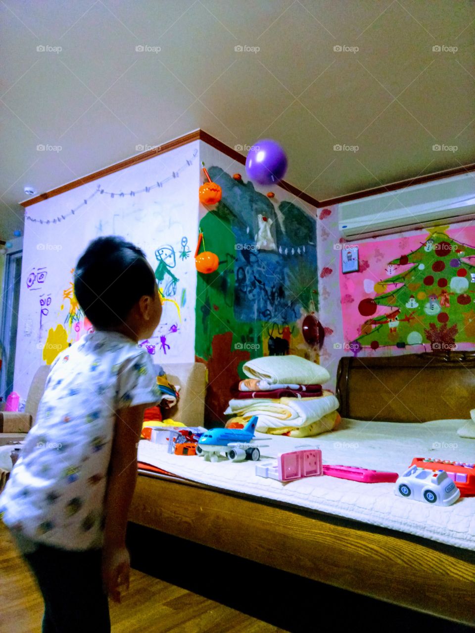 The Kids is playing the balloon inside home and its flying so high that's so impossible for him to catch.