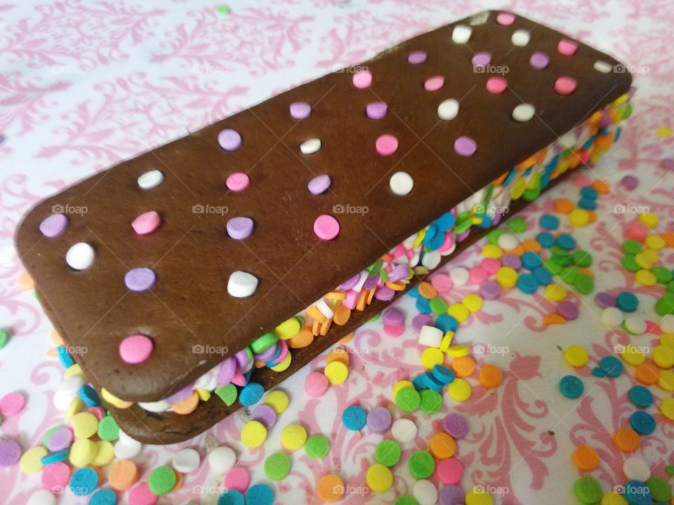ice cream sandwich plus. ice cream sandwich on pink and white damask background, colorful sprinkles on ice cream